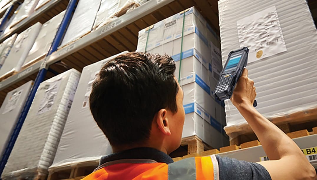 un homme scanne une etiquette avec code barre avec un terminal mobile